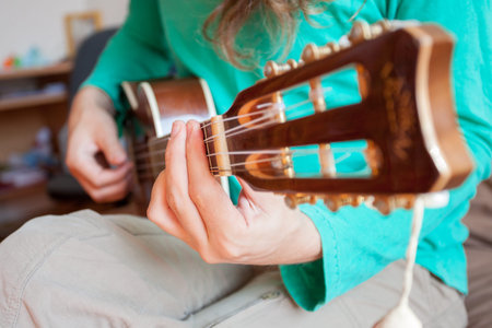Young man's hands playing an acoustic guitar ukulele at the home. A man playing ukulele in close up...