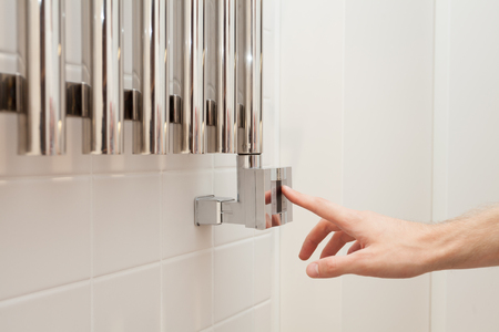 The man hand regulates thetemperature in the heated towel rail. の写真素材