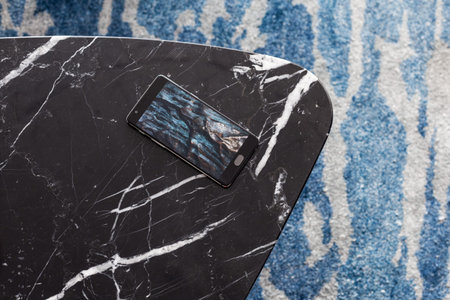A stool made of artificial stone stands on a carpet with fine nap, a top view. The mobile phone lies...