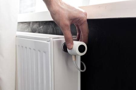 Radiator adjustment closeup. Man's hand adjusting radiator temperature.の写真素材