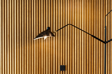 A minimalistic lighting element in the interior. Lamp made of metal against the background of wooden panelsの写真素材