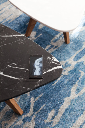 Two modern stool made of black and white artificial stone stands on a carpet with fine nap, a top view. The mobile phone lies on a new small chair.の写真素材