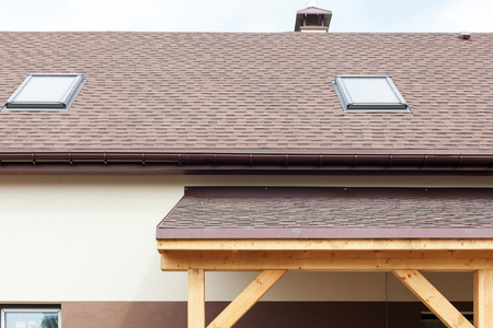 Window skylight on a roof with asphalt shingles or bitumen tiles under construction.の写真素材