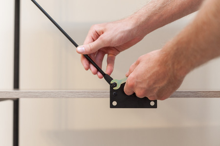 Close up of handyman adds the bookcase construction by screwing the bolts with a hexagonal wrench.の写真素材