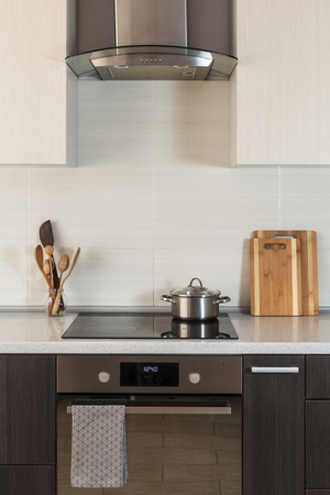 The pan is on a ceramic cooking plate in the new modern kitchen with extractor hood and ovenの写真素材