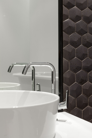 Element of bathroom interior with white sink and large mirror. New wash basin and black hexagonal tiles tile.の写真素材
