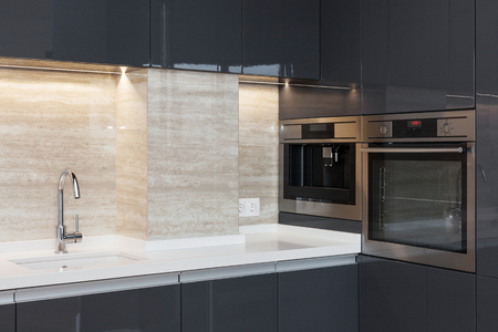 New modern kitchen with built in oven and chrome water tap. LED worktop illuminationの写真素材