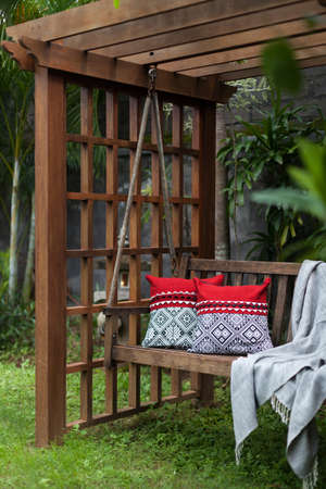 Fragment of wooden swing in the green garden with pillows and blanketの写真素材