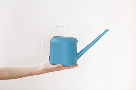Girl hold a watering-can in her hand on a light backgroundの写真素材