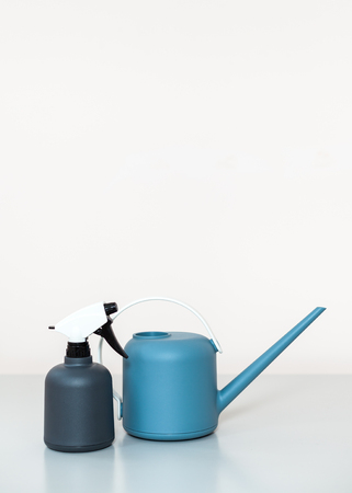 The watering can and sprayer are on the table on a light backgroundの写真素材