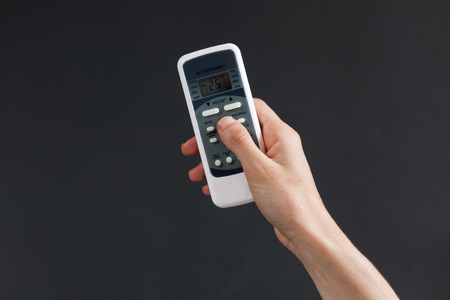 Hand using a remote control to activating air conditioning  on the dark backgroundの写真素材