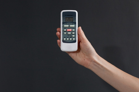 Hand using a remote control to activating air conditioning  on the dark backgroundの写真素材