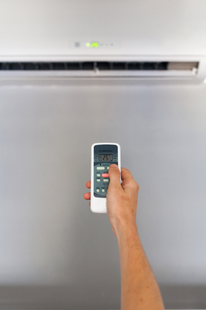 Hand using a remote control to activating air conditioningの写真素材