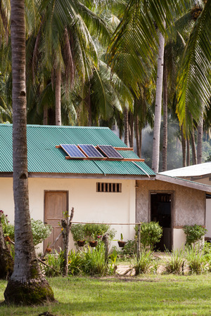 Solar panel on the house roof with a solar panels on top. House in the tropics among the palmsの写真素材