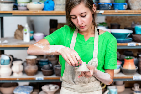 Check quality master class concept. Beautiful attractive pretty dreamy charming nice-looking confident lady in her casual green t-shirt workwear she look on cup in hands stand inside workspaceの写真素材