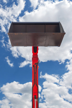 Low angle top view vertical photo of bulldozer bucket against peaceful blue sky