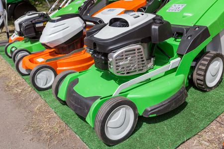 Photo of three new powerful green and orange gasoline lawn mowerの写真素材