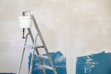 Photo of aluminum stairs for higher work with white bucket of putty coating against wall on reconstructionの写真素材