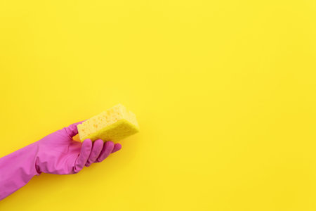 Woman holding polyurethane dish sponges for washing in hand isolated on yellow background with empty...