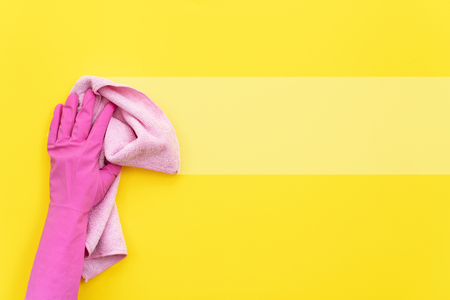 Woman in rubber gloves holding pink and soft cleaning towel in her hand isolated on yellow background with empty space for textの写真素材