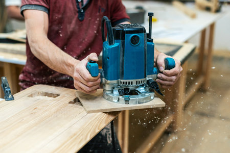 Manual wood concept. Cropped photo of cabinetmaker handyman stand half turn to camera hold electric tool in hand make furniture in garage work shop or workroomの写真素材