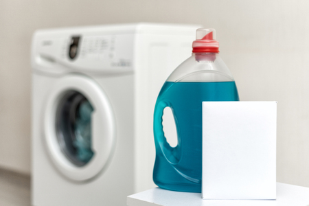 Close up photo of soap for laundry process standing against blurred and white washing machine inside light flat interiorの写真素材