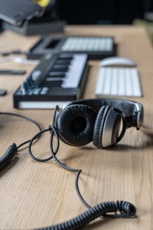 Vertical photo of headset and DJ instruments for making music lying on wooden table in sound recording studioの写真素材