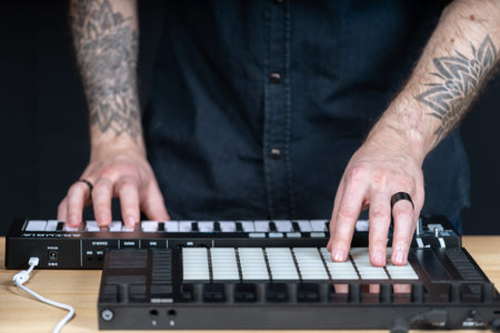 Cropped photo tattoo hands of DJ master man. He using professional instruments for creative music in...