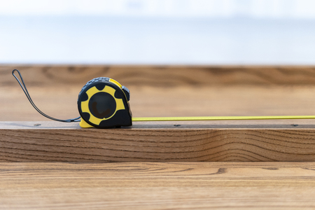 Side view and close up photo of special tool, measuring type equipment lying on hardwood plank board on new wooden desk or table topの写真素材