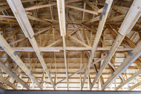 Timber frame house and real estate concept. Low angle top view photo of wooden attic with truss...