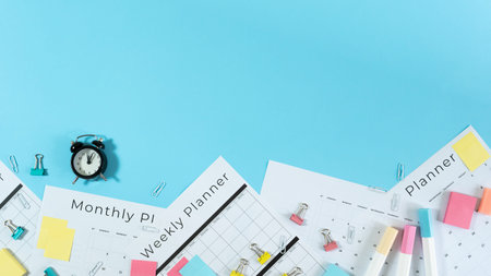 Panoramic view of monthly and weekly planner with copy space, alarm clock, stationery and sticky...