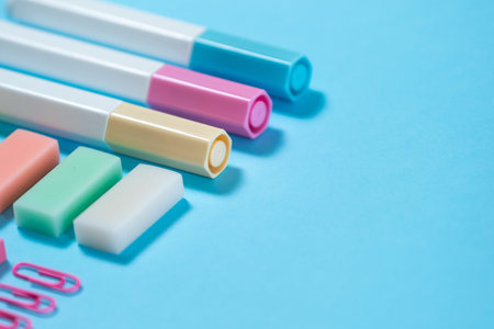 Selective focus of colorful stationery, marker and paperclip on pastel blue background with copy...