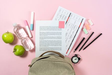 Back to school concept. Top view of backpack, green apples paper blanks and colorful stationery on pastel pink backgroundの写真素材