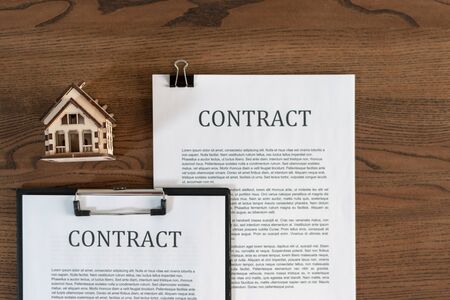 Top view symbol of house near contract or agreement in clipboard on wooden table in officeの写真素材