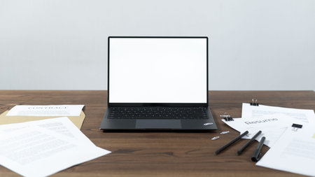 Modern laptop computer with blank screen and copy space at workplace. Document and stationery on...