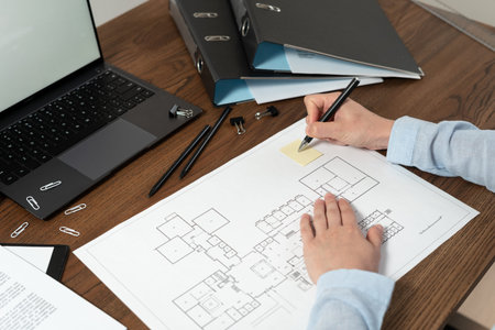 Cropped view of engineer designer working with architecture plan, making notes and mark at...