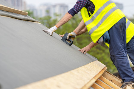 Man working with stapler and special waterproof bitumen membrane. Mature and professional contractor...