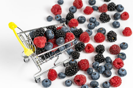 High angle view and close up of shopping cart trolley with ripe blueberry, blackberry and raspberry...