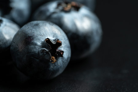 Selective focus and macro view of ripe blueberries fruit on black background with copy spaceの写真素材
