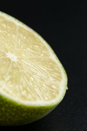 Vertical photo and macro view of delicious citrus, half juicy lemon fruit on black background with copy spaceの写真素材