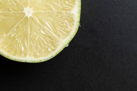 Close up view of cut delicious citrus, slice juicy lemon fruit on black background with copy spaceの写真素材