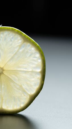 Vertical photo and close up view of delicious citrus, slice juicy lemon fruit on black background with copy spaceの写真素材