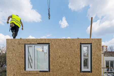 Process of construction new and modern modular house. Builder man standing on sip panel in special...