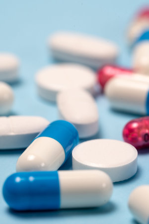 Selective focus and macro view of set of different and colorful medical pills lying on blue...
