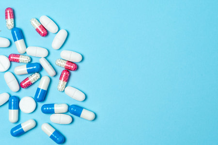 Top view of set of different and colorful medical pills lying on blue background with copy space