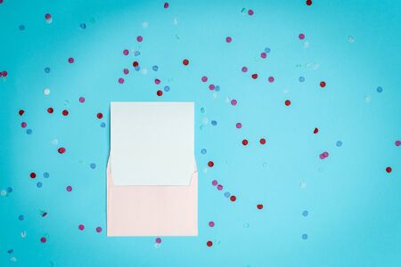 Happy anniversary! Flat lay and high angle above top view of letter in envelope lying isolated shine blue background with copy or empty space for text with paper and colorful confetti decorationsの写真素材