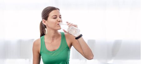 Panoramic view of happy young woman drinking water from plastic bottle and smilingの写真素材