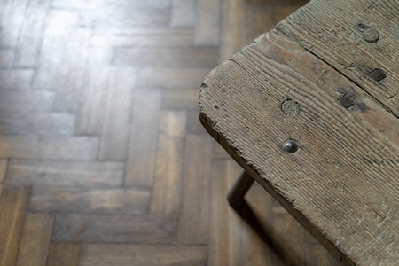 Wooden table on parquet floor at cozy house with old texture background, detail of furniture