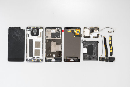 Top view group of broken modern smartphone details lying on table with copy space in service center