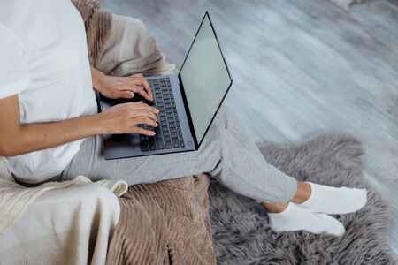 Cropped view of busy young adult freelancer woman spending free time at home, working on laptop computer with blank screen and copy space on displayの写真素材